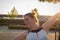 The young woman rejoices morning sun at a bus stop