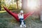 Young woman relaxing with her dog in orange hammock. Camping outdoors. autumn season at sunset