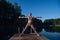 Young woman relaxing by the lake at sunset, harms outstretched. Doing youga in the morning at forest lake.