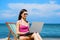 A young woman relaxing with a laptop on a beautiful beach