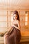 Young woman relaxing in a sauna dressed in a towel. Interior of new Finnish sauna, infrared panels for medical