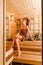 Young woman relaxing in a sauna dressed in a towel. Interior of new Finnish sauna, infrared panels for medical