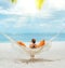 Young woman relaxing in wicker hammock on the sandy beach on Mauritius coast and enjoying wide ocean view waves. Exotic countries