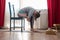 Young woman in relaxing yoga pose called balasana or child pose sitting on chair