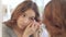 Young woman removing contact lenses for eyes at mirror in home bathroom