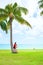 Young woman resting against coconut palm tree by hawaiian ocean