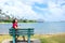 Young woman resting on park bench along Hawaiian ocean