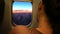 Young woman resting on the plane during the flight. She sleeps and watches the beautiful sunrise through the porthole.