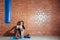 Young woman resting after a workout in the gym. A girl sits on a background of a brick wall in the hall of boxing