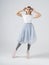 A young woman in retro quad roller skates listening to music and holds headphones a white cyclorama background