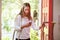 Young Woman Returning Home For Work Looking At Mobile Phone