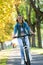 Young woman ride bike in autumn park. Enjoying while cycling in nature during autumn day