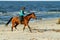 Young woman riding horse on the beach.