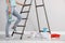 Young woman with roller near ladder indoors, closeup