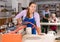 Young woman rolls out clay on craft machine clay press roller in studio