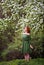 Young woman in romantic green dress in a blooming apple garden.