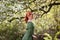 Young woman in romantic green dress in a blooming apple garden.