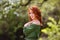 Young woman in romantic green dress in a blooming apple garden.