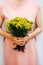 Young woman in a rosy dress holding a bunch of colorful picked w