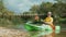 A young woman rowing in kayak to the shore, and looks around smiling. Real time