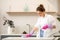 A young woman in rubber gloves sprays cleaning agent on the countertop in the kitchen. Cleaning