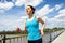 Young woman runing in the city over the brige in sun light.