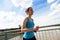 Young woman runing in the city over the brige in sun light.