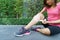 Young woman runner knee being applied bandage by herself in park