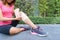 Young woman runner knee being applied bandage by herself in park