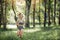 Young woman runner listening music on headphones while running on tropical rainforest trail in the morning