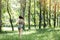 Young woman runner listening music on headphones while running on tropical rainforest trail in the morning