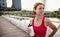 Young woman runner with water bottle in city, resting. Copy space.