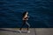 young woman running along the beach with amazing big ocean waves on background