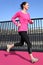 Young woman running on a bright pink road