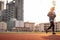 Young woman is running on racetrack at sunset, building behind