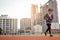 Young woman is running on racetrack at sunset, building behind