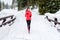 Young woman running on snow in winter mountains wearing warm clothing gloves in snow weather