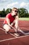 young woman on running track lacing her shoes