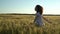 A young woman runs across the field in a white dress. Happy girl in a green wheat field. Slow motion.