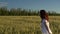 A young woman runs across the field in a white dress. Happy girl in a green wheat field. Slow motion.