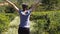 Young woman runs among a tea shrubs at plantation and raises hands. Unrecognizable girl jogs among lush bushes at field