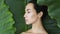 Young woman`s face surrounded by tropical leaves.