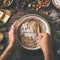 Young woman`s hands cooking christmas fruit cake. Wooden table with baking ingredients