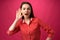 Young woman's reaction on what she heard, surprise, on pink background