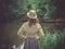 Young woman with safari hat by pond in forest