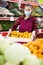 Young woman salesman in mask carrying box with plums