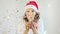 Young woman in Santa Claus hat dancing and having fun. Close up of female in Christmas hat and dancing in confetti
