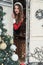 Young woman in santa costume decorates the Christmas tree at winter campsite