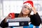 Young woman in santa hat exhausted in office