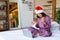 Young woman in Santa hat and pyjama. New normal, quarantine, talking with friends on video call. Celebrating Christmas -